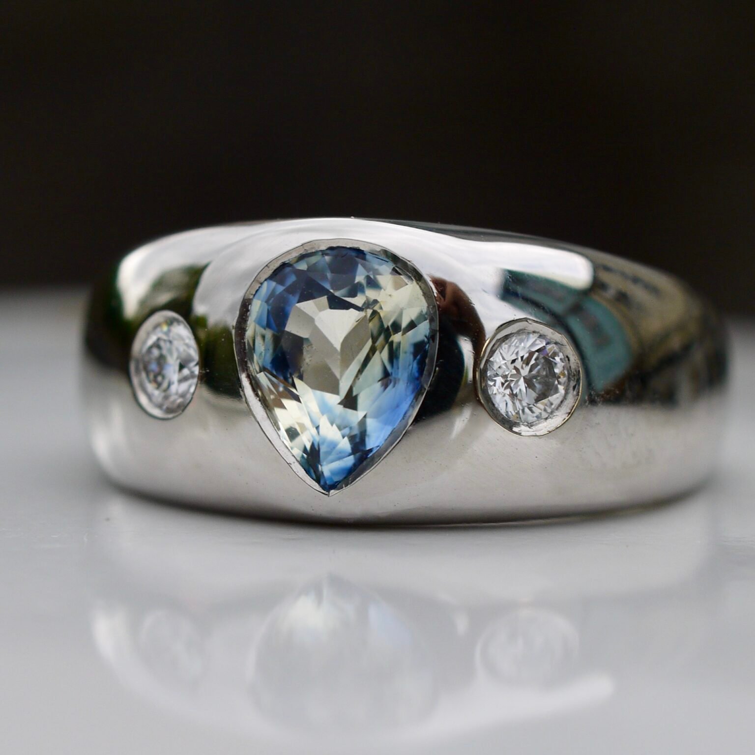 a silver ring with a blue stone and three diamonds